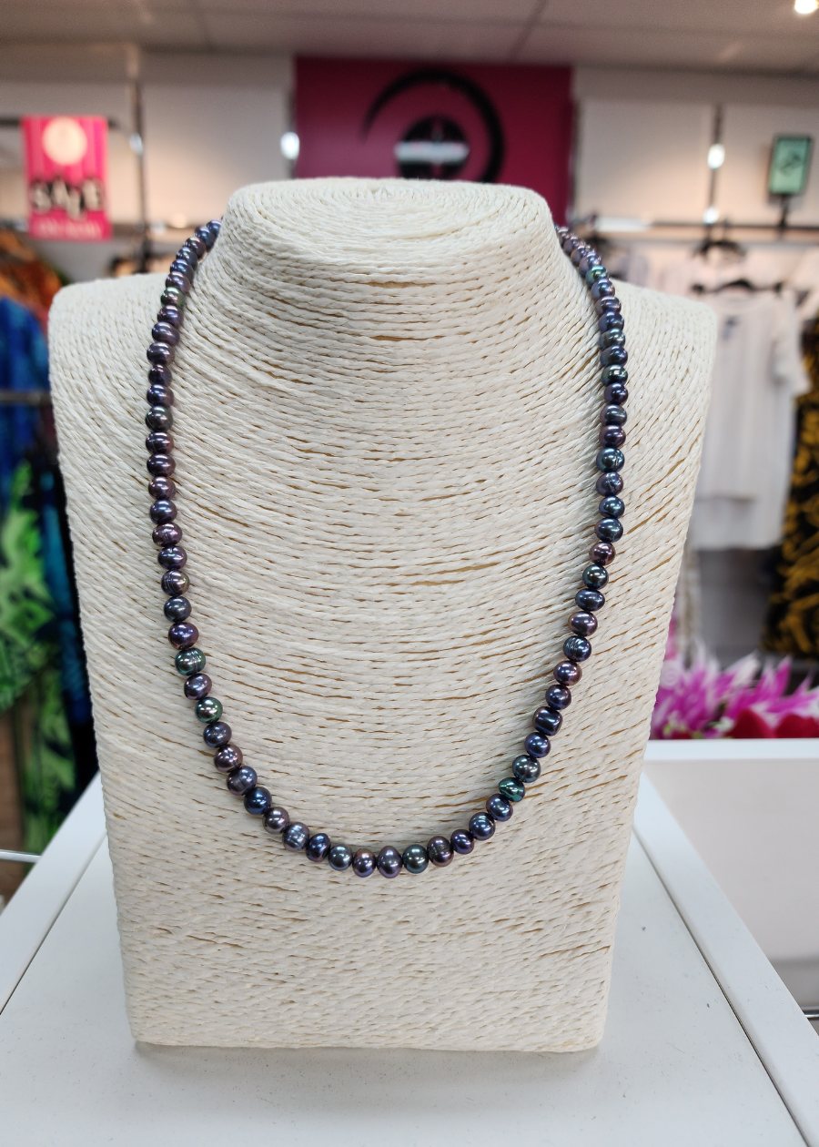 A necklace with black freshwater pearls displayed on a mannequin bust, featuring a lobster claw clasp and chain extension.