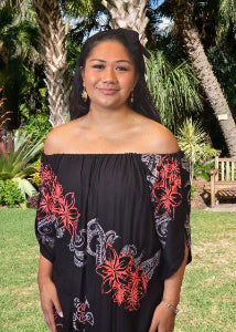 Woman wearing a black off-shoulder dress with red floral patterns in a garden setting